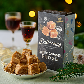 A plate with a pile of fudge cubes on it, with 2 small glasses of port in the background