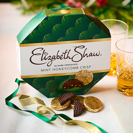 Foil covered mint chocolates beside a dark green box