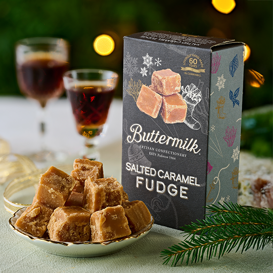 A plate with a pile of fudge cubes on it, with 2 small glasses of port in the background