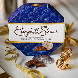 A blue Hexagonal box with gold ribbon at the side, and some chocolate mints at the front